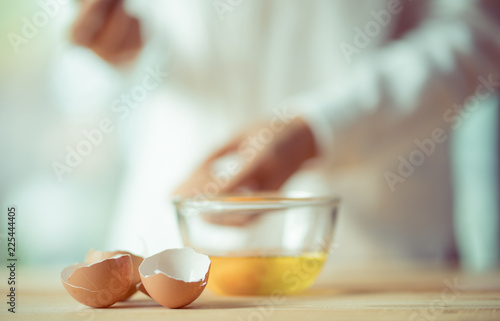 egg shell and bowl with blurred woman as background, cozy kitchen style