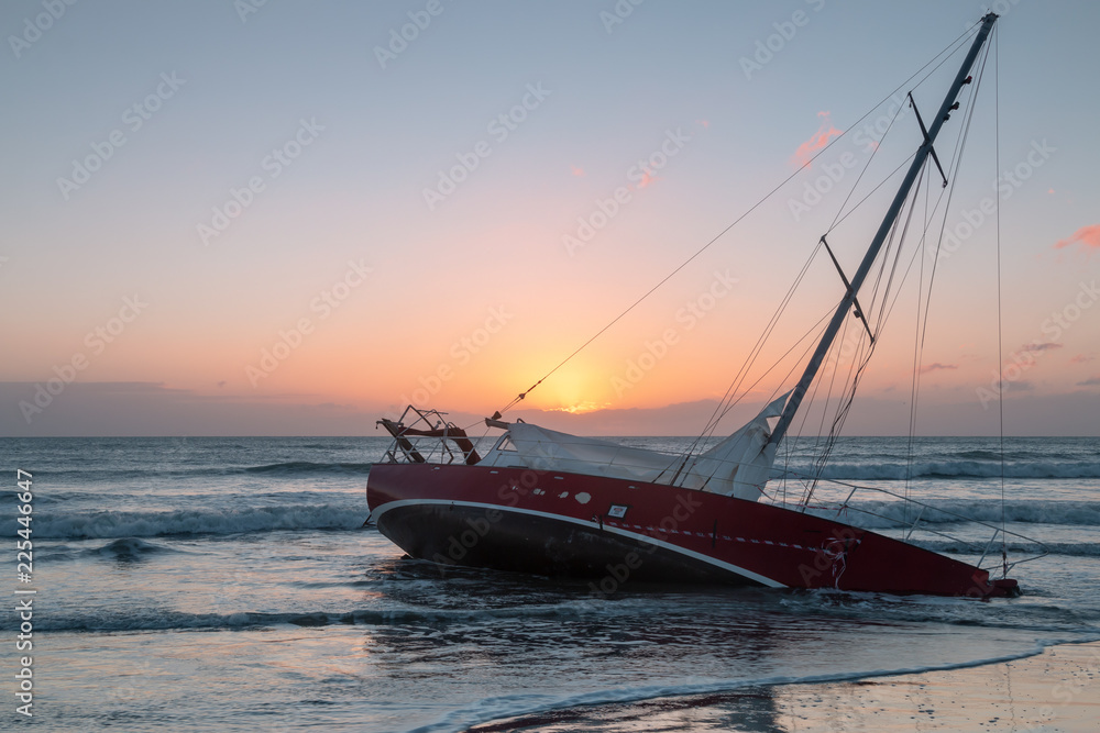 Sunken boat on ocean shore at sunrise