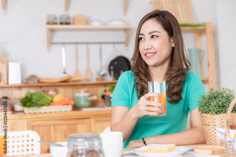 mother drinking orange juice in the kitchen on the wood table mother drinking orange juice in the kitchen on the wood table