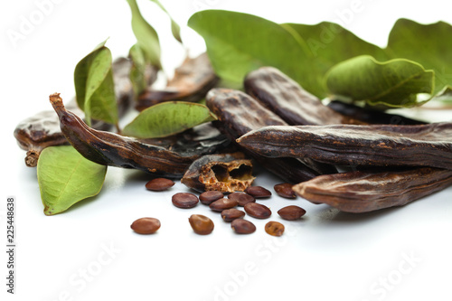 Carob bean. Healthy organic sweet carob pods with seeds and leaves on white background