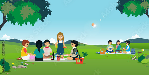 Boys and girls are eating picnic in the garden.