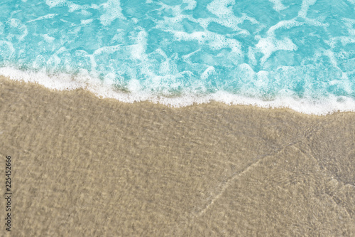 Fototapeta Naklejka Na Ścianę i Meble -  Soft wave of blue ocean on sandy beach. Background / Sand and wave at the beach background. Drop space on bottom for text and other.