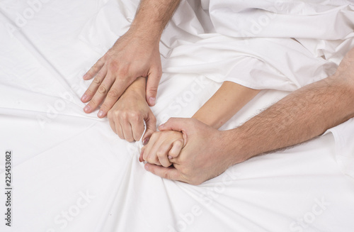 Close up hands of a couple make love hot sex on a bed.