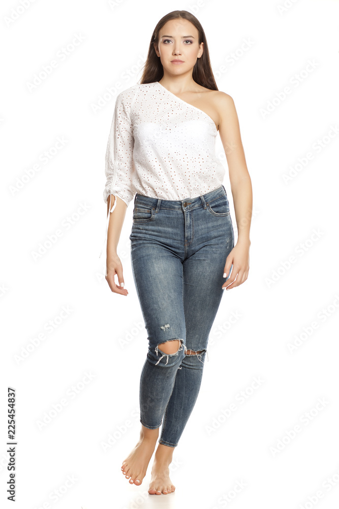 Barefoot young beautiful girl in jeans walking on white backgeound Barefoot young beautiful girl in jeans walking on white backgeound