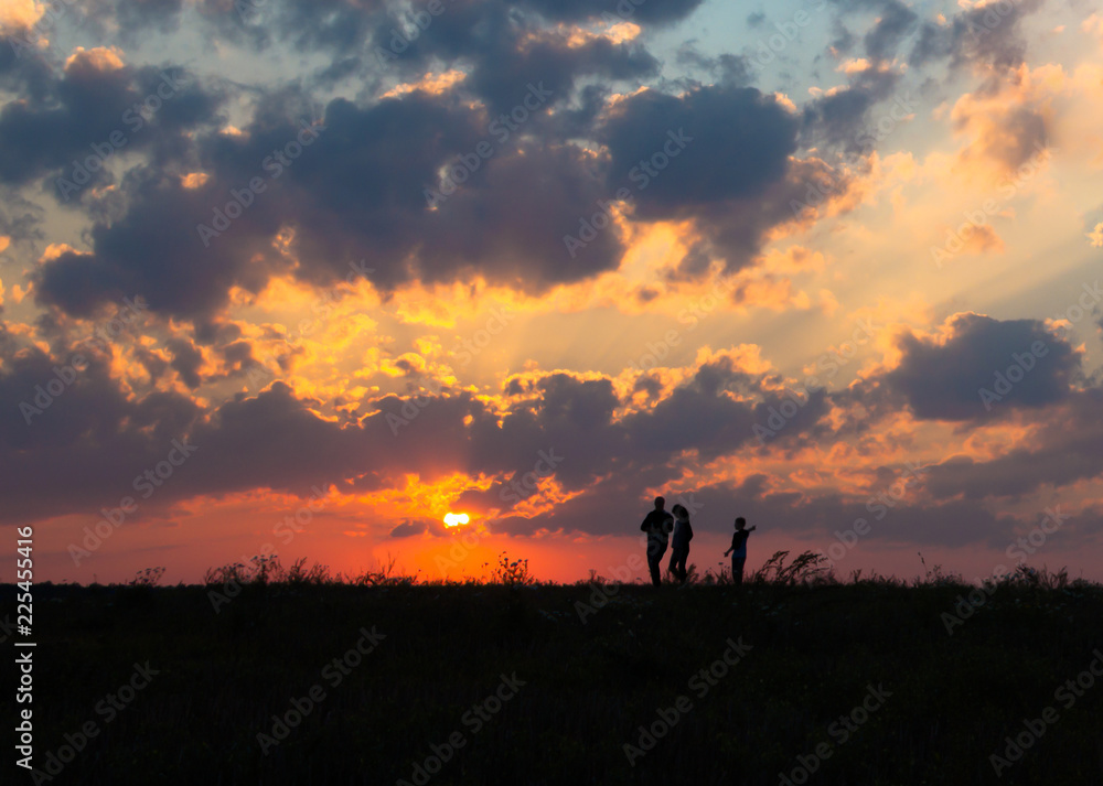 sunset dawn sun rays over field sky field family walking near the sun on the horizon silhouette