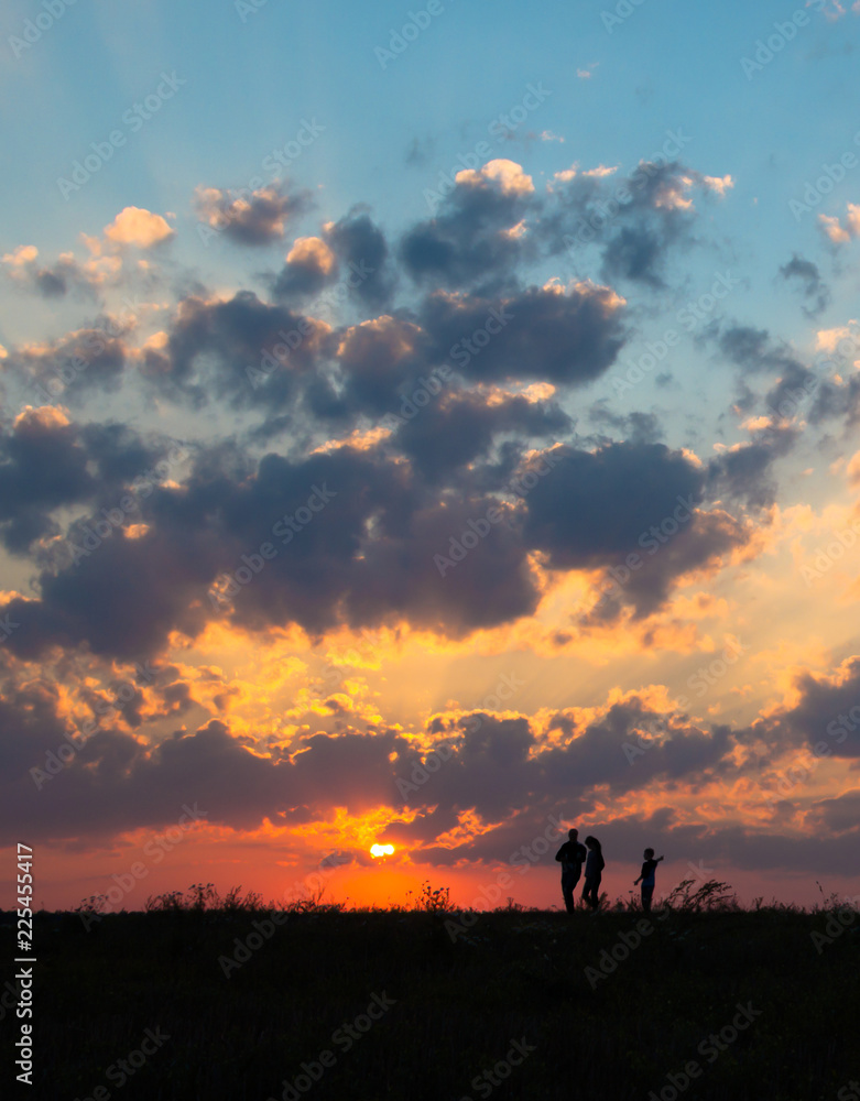 sunset dawn sun rays over field sky field family walking near the sun on the horizon silhouette