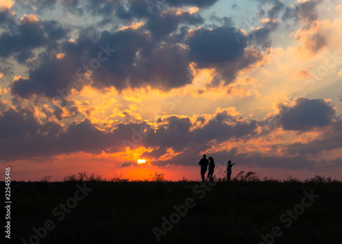 sunset dawn sun rays over field sky field family walking near the sun on the horizon silhouette © Volha