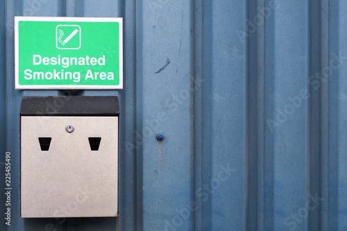 Designated smoking area sign and metal ash tray at work business wall © Richard Johnson