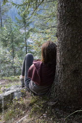 Girl sitting under a tree and thinking at sunset