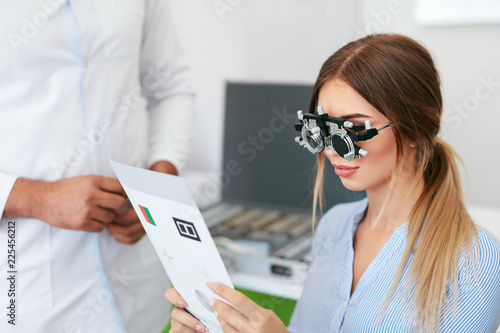 Eye Exam. Woman In Optometry Glasses Reading Eye Test Card