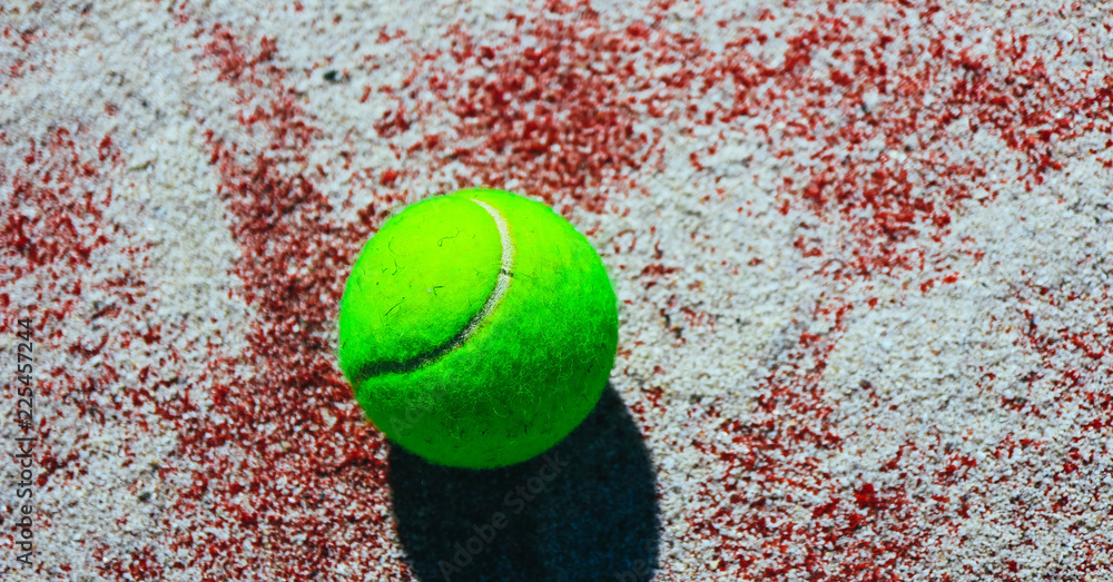 One green tennis ball on the sunny court, sport competition concept. Tennis backdrop, close up.