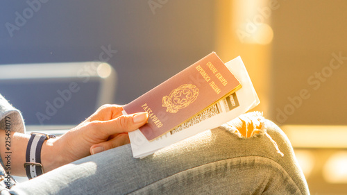 Italian passport and boarding pass in the hands of woman awaiting departure flight in waiting hall - concept of independence and easy traveling in Europe photo