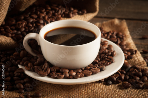 Coffee cup and beans on a rustic background. Coffee Espresso and a piece of cake with a curl. Cup of Coffee and coffee beans on table. © xander21
