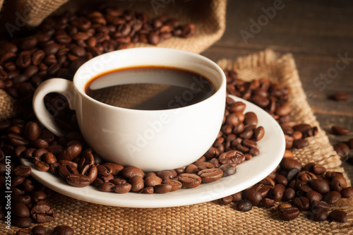 Coffee cup and beans on a rustic background. Coffee Espresso and a piece of cake with a curl. Cup of Coffee and coffee beans on table.