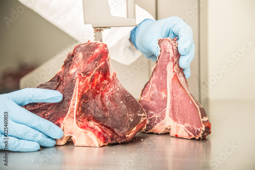 worker on band saw cut meat in a meat shop