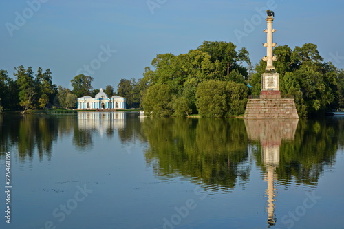 Monument chesme column and pavilion grotto with reflection at blue water on big lake in catherine park. Sunny summer day. Tsarskoe selo, city Pushkin, Saint-Petersburg, Russia, Europe photo