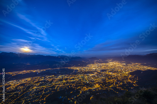 Aerial of Grenoble at night with moon rising over the mountains © florent