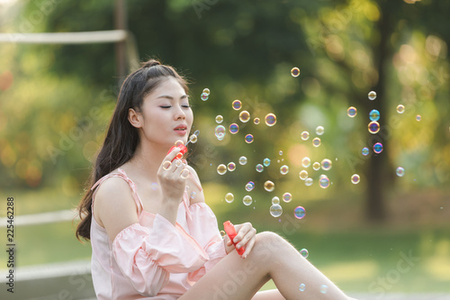 young woman sitting on the bridge playing bubble balloons in the garden life style 