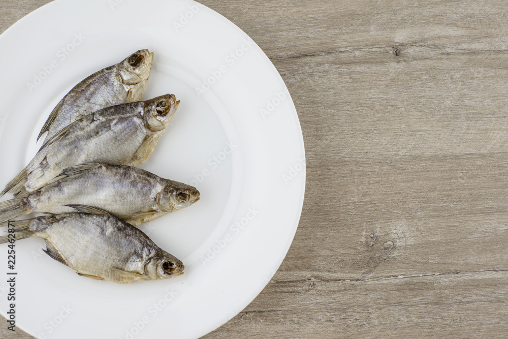 beer snack: 4 sun-dried salted freshwater fish on a white plate - a source of vitamins and protein beer snack: 4 sun-dried salted freshwater fish on a white plate - a source of vitamins and protein