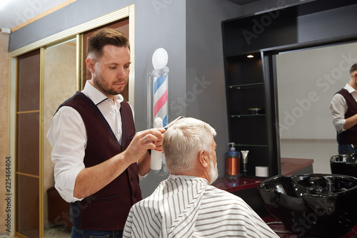 Professional barber grooming man's hair in barbershop.