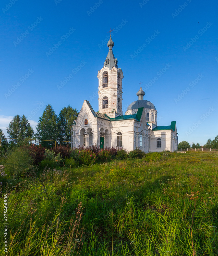 The building of the old Russian church against the blue sky and green grass, Kirov region, Russia
