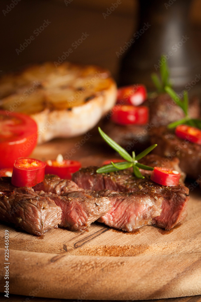 grilled fillet steak with tomatoes and roast vegetables on an old wooden board, background. grilled fillet steak with tomatoes and roast vegetables on an old wooden board, background.