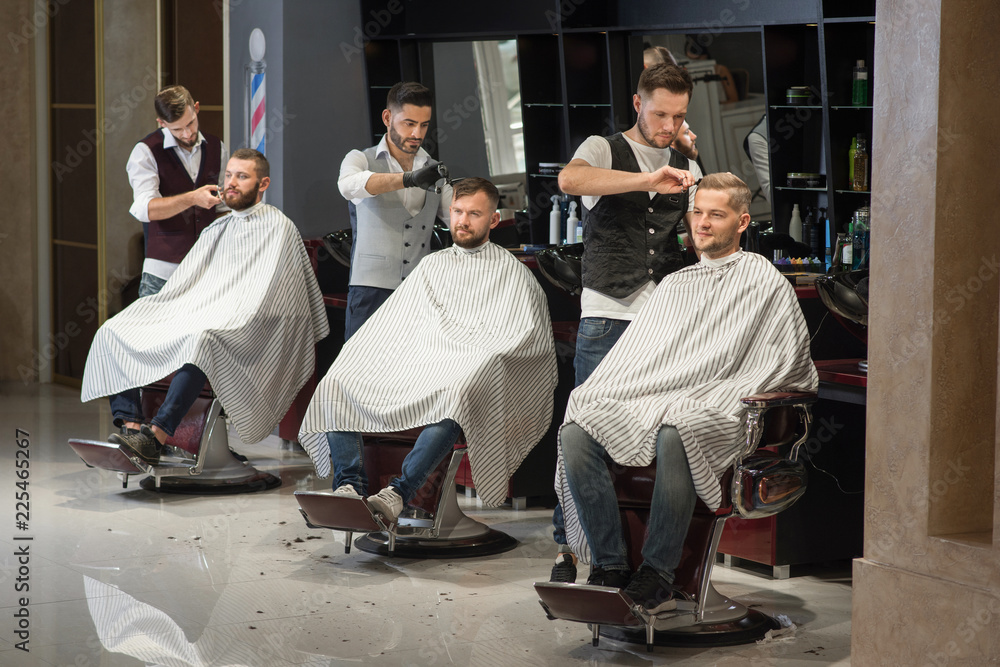 Barbers grooming and styling haircuts of clients in barbershop. Barbers grooming and styling haircuts of clients in barbershop.