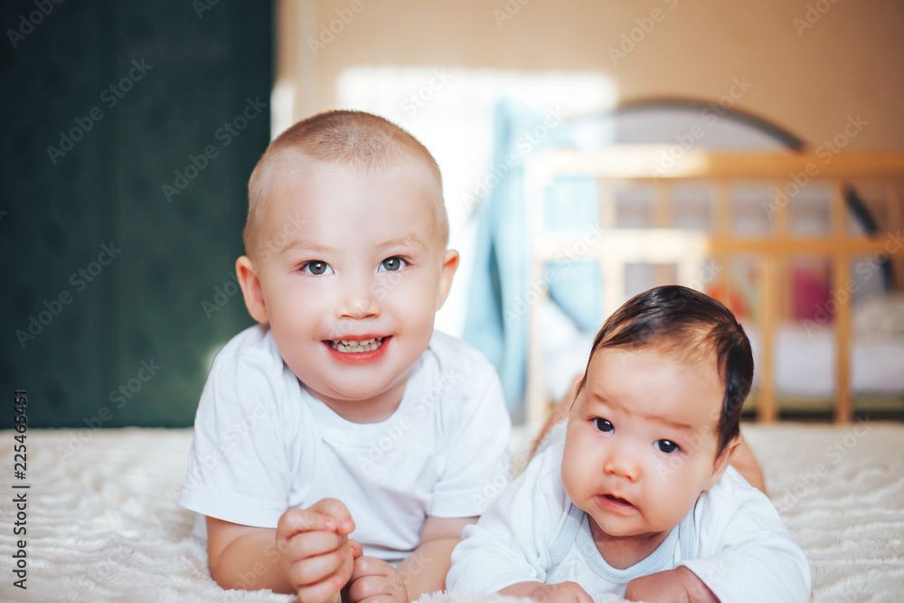 Elder brother and newborn baby sister lying on bed at home Elder brother and newborn baby sister lying on bed at home