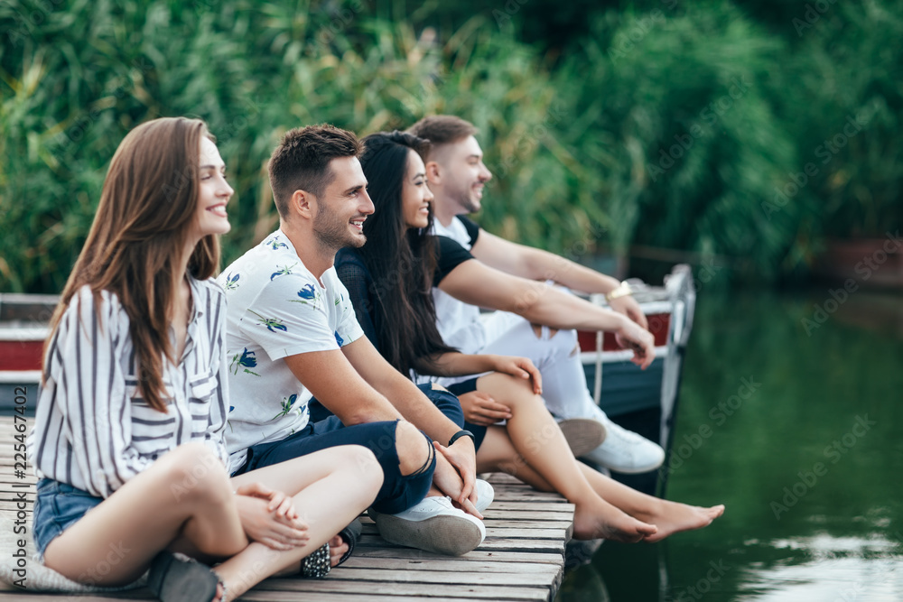 Group of happy young friends relaxing on river pier