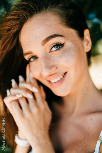 Closeup emotional  lifestyle portrait of adorable cute beautiful young cheerful coquette girl with big natural lips and blue happy eyes outdoor at nature.  Cute attractive smiling teen face. photo