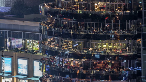 Aerial vew of Dubai Marina promenade with restaurants from skyscraper night timelapse, United Arab Emirates.