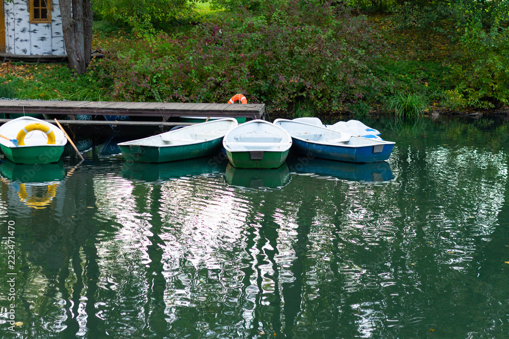Obraz premium Empty boats in a row in the calm water of a pond or lake in autumn.