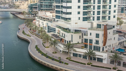 Promenade and canal in Dubai Marina with luxury skyscrapers and yachts around timelapse, United Arab Emirates