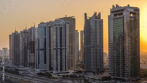 Aerial view of Jumeirah lakes towers skyscrapers night to day timelapse with traffic on sheikh zayed road.