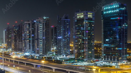 Aerial view of Jumeirah lakes towers skyscrapers during all night timelapse with traffic on sheikh zayed road. © neiezhmakov