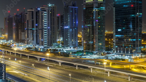 Fototapeta Naklejka Na Ścianę i Meble -  Aerial view of Jumeirah lakes towers skyscrapers during all night timelapse with traffic on sheikh zayed road.