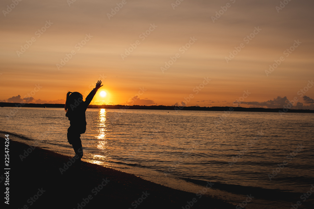 Fototapeta premium silhouette of a child on the background of the setting sun on the beach