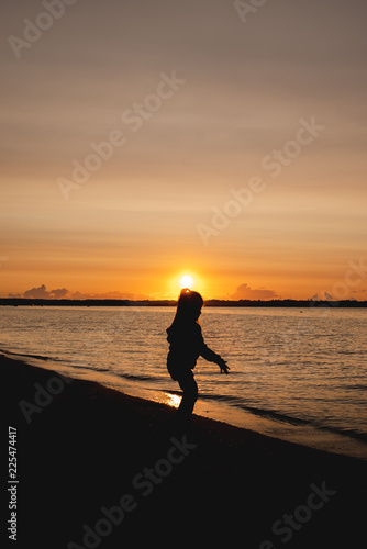 silhouette of a child on the background of the setting sun on the beach