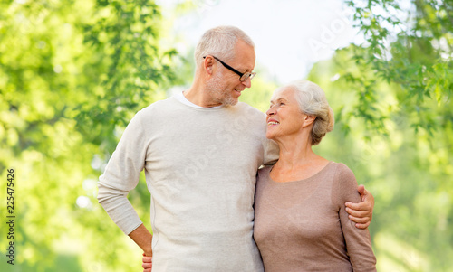old age and people concept - happy senior couple hugging over green natural background