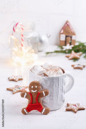 Cup of traditional hot chocolate with marshmallows and gingerbread on white table. Christmas drink in New Year decorations.