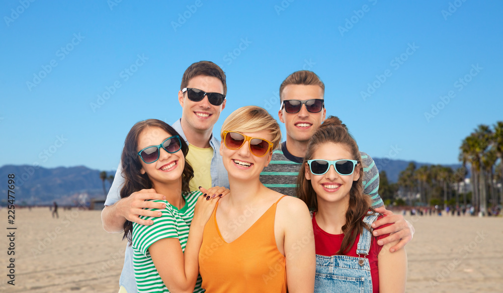 friendship, summer and people concept - group of happy smiling friends in sunglasses hugging over venice beach background in california friendship, summer and people concept - group of happy smiling friends in sunglasses hugging over venice beach background in california