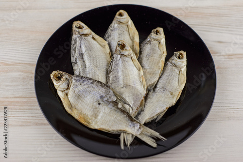 beer snack: 6 sun-dried freshwater salt fish on black plate - a source of vitamins and protein, gray table, placed in the shape of a maple leaf photo