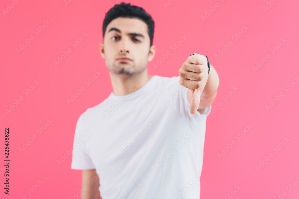 grimacing handsome man showing thumb down isolated on pink grimacing handsome man showing thumb down isolated on pink