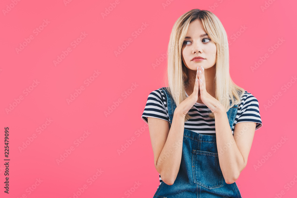 sad beautiful girl in denim overall looking away with hands in namaste gesture isolated on pink sad beautiful girl in denim overall looking away with hands in namaste gesture isolated on pink