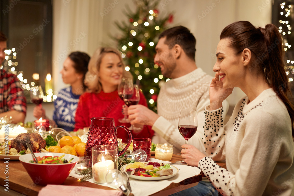 holidays, communication and celebration concept - happy young woman calling on smartphone and having christmas dinner with friends at home