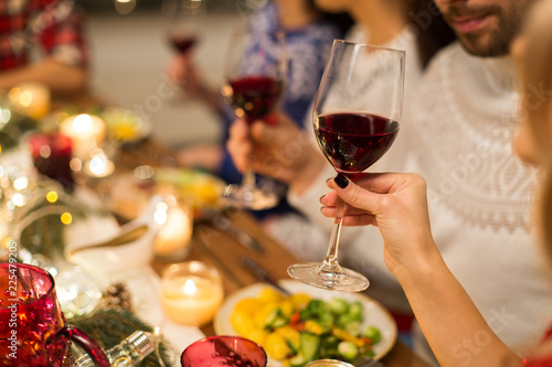 holidays and celebration concept - close up of happy friends having christmas dinner and drinking red wine