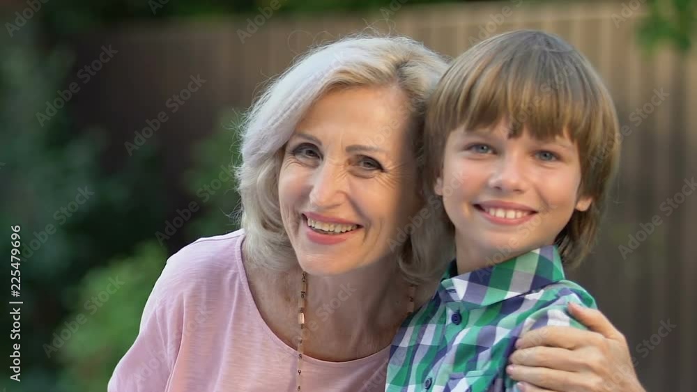 Cheerful grandmother talking to little boy and smiling at camera, happy family Cheerful grandmother talking to little boy and smiling at camera, happy family