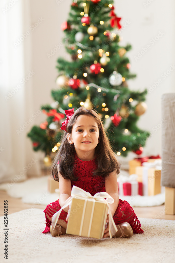 christmas, holidays and childhood concept - happy girl with gift box at home christmas, holidays and childhood concept - happy girl with gift box at home