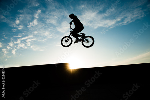 extreme jumping high rider on bicycle flying on beautiful sky sunset backdrop