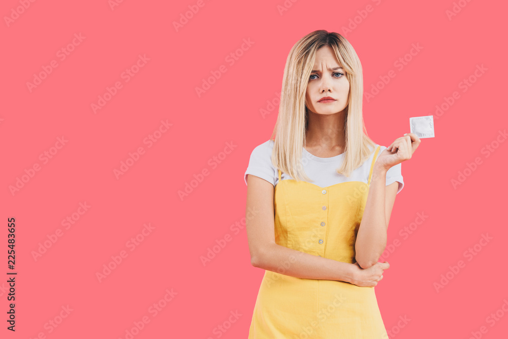 emotional young stylish woman holding condom isolated on pink emotional young stylish woman holding condom isolated on pink
